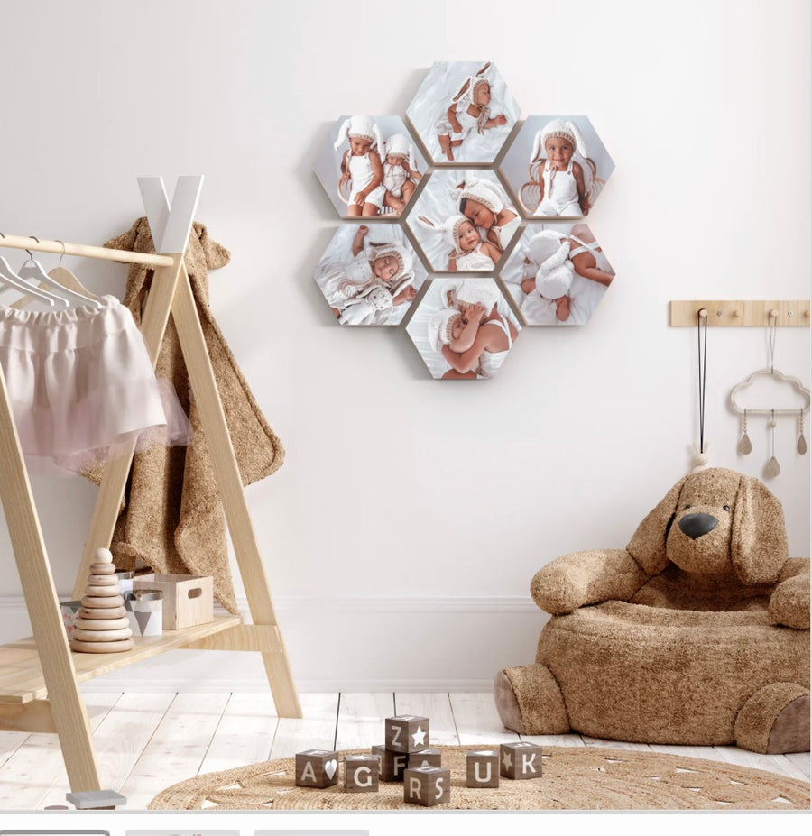 Seven hexagonal wooden photo blocks with baby photos arranged in a honeycomb on a nursery wall